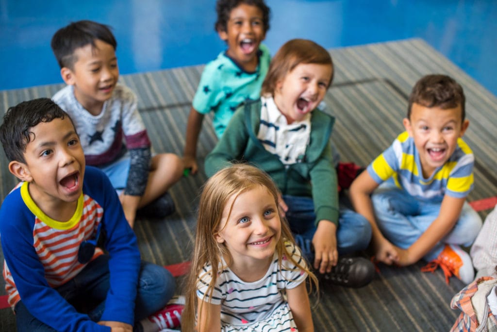 Portrait of a group of young children standing in a line in the hallway of a school