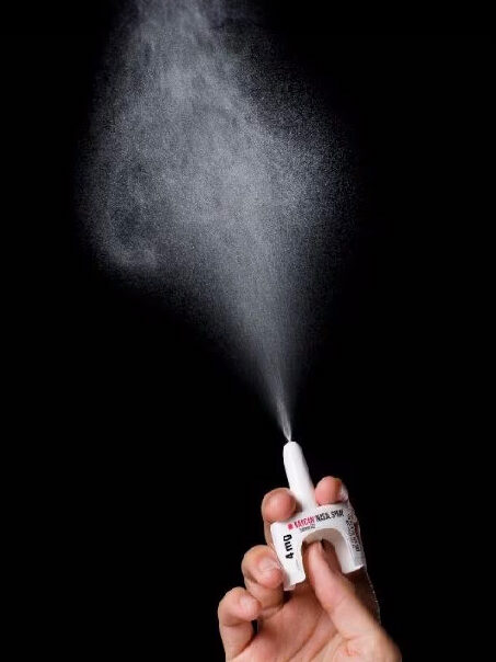 a hand spraying a narcan spray into the air